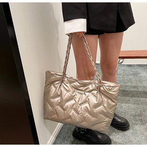 Detail of champagne gold quilted tote bag with woven handles and metallic finish