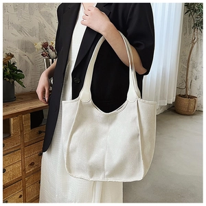 Detail shot of a minimalist cream-white tote bag with wide shoulder straps on a model