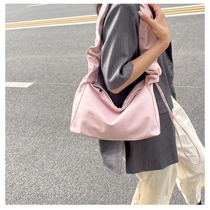 Pink baguette bag with ruched cloud shoulder strap shown on grey oversized blazer