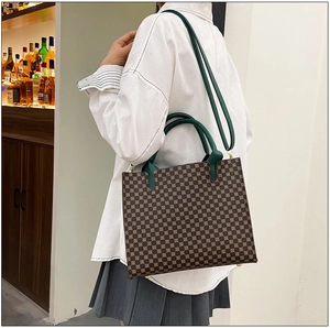 Detail of a large brown tote bag with yellow geometric patterns and dark green handles
