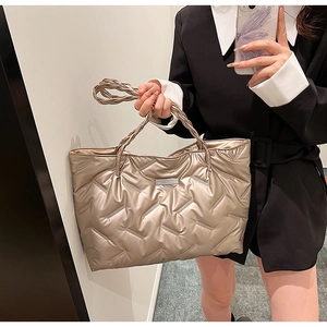 Detailed side view of champagne gold quilted tote bag with woven handles and metallic finish