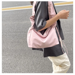 Outdoor street style shot of pink pleated hobo bag with wide shoulder strap