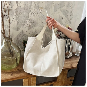 Detail of a large cream nylon tote bag with wide handles shown in a cozy home setting