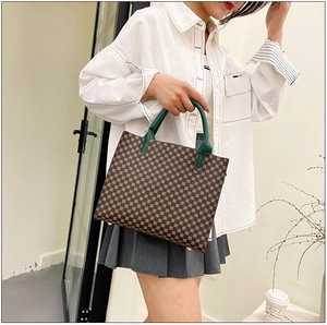 Detail of vintage tote bag featuring geometric print and dark green leather handles
