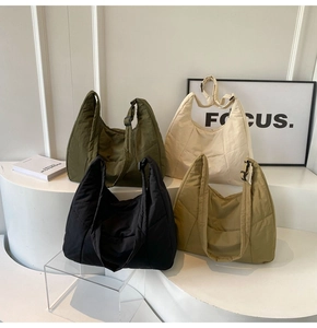 Detailed display of quilted nylon tote bags in four colors on minimalist white stands