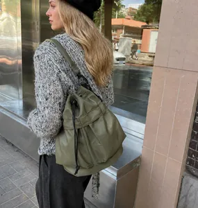 Outdoor shot of an army green nylon drawstring bucket bag with adjustable straps