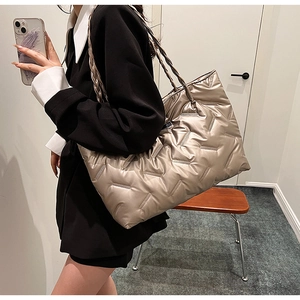 Detailed close-up of champagne gold quilted puffer tote bag with glossy metallic finish