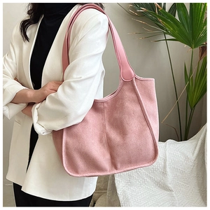 Side view of a pink plush tote bag worn by a model in a cozy indoor setting