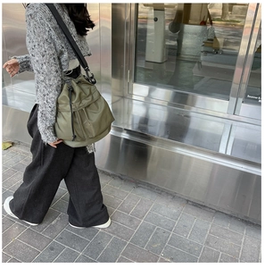 Detail view of army green nylon drawstring bucket bag with adjustable black shoulder strap