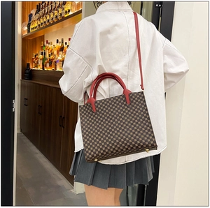 Detail of vintage geometric tote bag with red handles shown on model in a warm setting