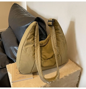 Detailed close-up of quilted nylon crescent shoulder bag on a stone surface