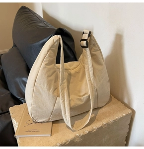 Detail of beige quilted nylon tote bag with wide strap and black adjustment buckle