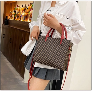 Close-up of brown geometric print tote bag with red leather handles and strap