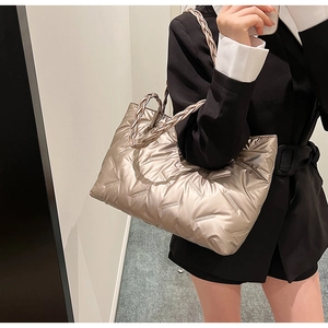 Detail of metallic champagne puffer tote bag with quilted texture and braided strap