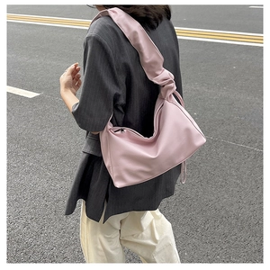 Pink baguette bag with pleated shoulder strap styled with casual suit outdoors