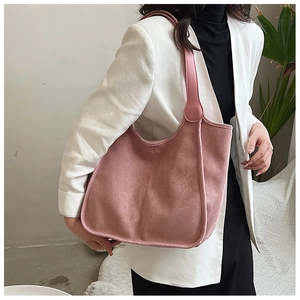 Detail shot of a soft pink suede-textured hobo tote bag worn with a white blazer