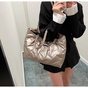 Detailed close-up of champagne gold down tote bag featuring braided strap and quilted texture