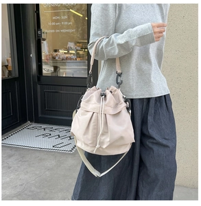 Detailed shot of a beige nylon drawstring bucket bag with adjustable shoulder straps and top handle