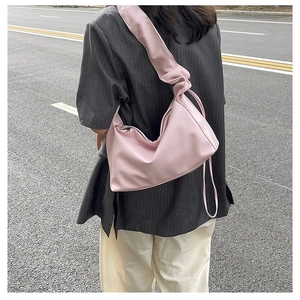 Detail view of pink baguette bag showing pleated strap design and smooth texture