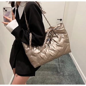 Detail of champagne gold quilted tote bag with unique braided shoulder strap and glossy finish