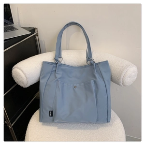 Detail of grey-blue nylon tote bag with front snap pocket and sturdy metal ring connectors