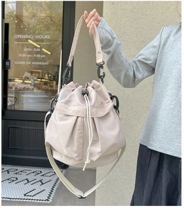 Macro detail of beige nylon bucket bag featuring drawstring closure and pleated texture