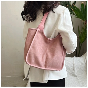 Detailed texture of a soft pink suede tote bag worn over the shoulder by a model