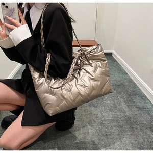 Detail of champagne gold quilted tote bag with double woven straps and glossy metallic finish