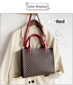 Close-up of brown monogram tote bag with red leather handles and gold metal buckle