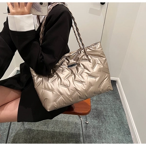 Macro detail of champagne gold quilted tote bag with metallic sheen and braided handles