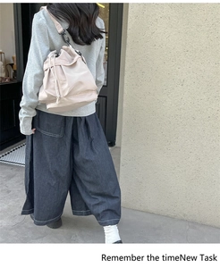 Close-up of beige nylon bucket bag featuring a drawstring closure and bottom zip compartment