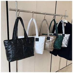 Quilted puffer tote bags in five colors displayed on a minimalist showroom rack