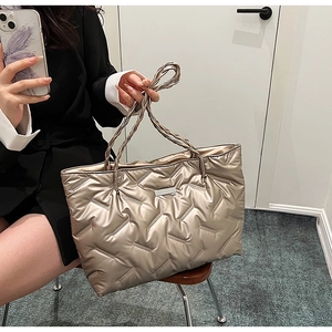 Detailed view of quilted puffer tote bag in champagne gold with woven top handles