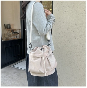 Close-up of beige nylon bucket bag featuring drawstring closure and wide fabric strap