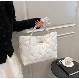 Detailed side view of a pearl white quilted tote bag with metallic texture and handles