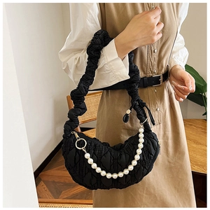 Detail of black quilted cloud bag featuring drawstring pleated strap and pearl chain detail