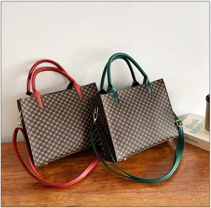 Detail of vintage monogram tote bags with red and green leather trim on wooden table