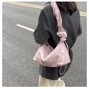 Pink pleated baguette cloud bag with ruched strap detail worn with grey blazer