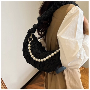 Detail of black quilted hobo bag featuring pearl chain and elegant ruffled shoulder strap