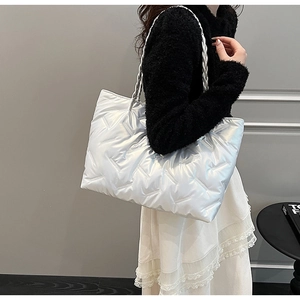 Silver quilted tote bag featuring metallic finish and woven rope handles in detail