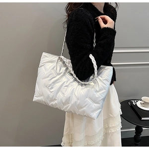 Detail of silver quilted tote bag featuring metallic V-shape texture and woven rope handle