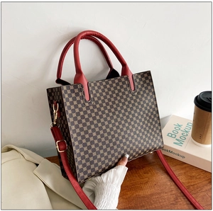 Detail shot of vintage brown monogram tote with red leather handles and gold hardware