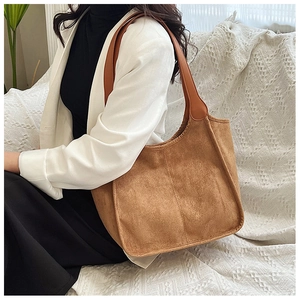 Close-up of a brown frosted leather large tote bag styled with a white blazer for casual wear