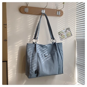 Close-up of Morandi blue tote bag with metallic ring handle and front snap pocket