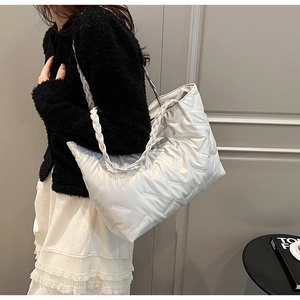 Silver quilted tote bag with chunky rope handles shown on a model in a lifestyle setting