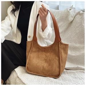 Detail of a large brown suede tote bag with contrast stitching and wide leather handles