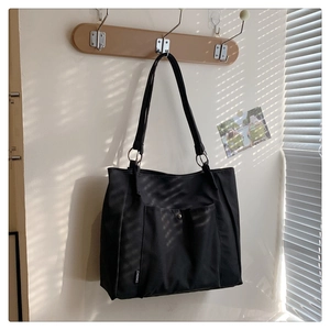 Detail of black nylon tote bag featuring silver metal rings and outer pocket detail