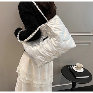 Detail of white quilted puffer tote bag with braided handle and glossy finish