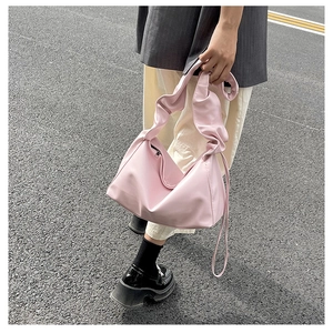 Detail showing the light pink pleated croissant bag with soft shoulder strap texture