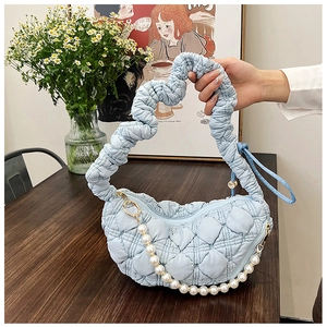 Close-up of light blue quilted cloud bag featuring large pearl chain and scrunchie handle